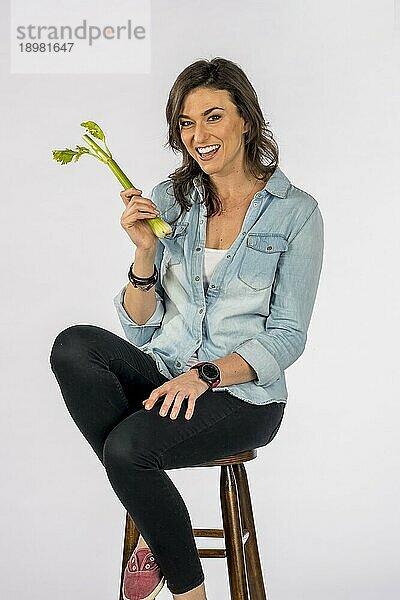 Gorgeous langhaarige Brünette Modell Essen Gemüse gegen weißen Hintergrund in einem Studio Umwelt