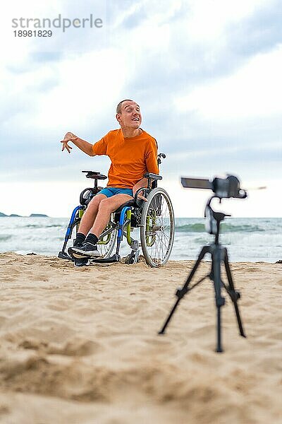 Eine behinderte Person im Rollstuhl nimmt am Strand ein Video auf