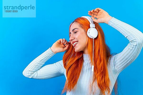 Rothaarige Frau im Studio Fotografie lächelnd tanzen auf einem blauen Hintergrund