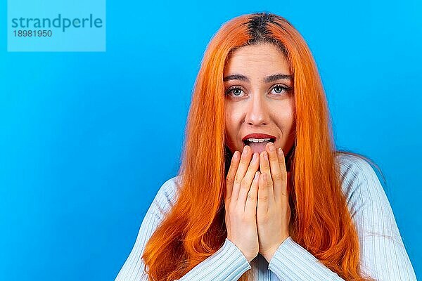 Rothaarige Frau im Studio Fotografie macht die Geste bitte auf einem blauen Hintergrund