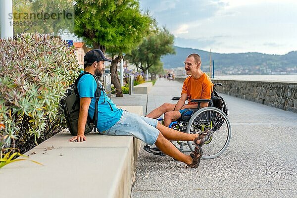 Eine behinderte Person in einem Rollstuhl am Strand mit einem Freund