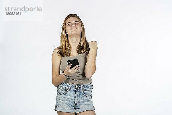 Ein schönes blondes Teenager Model spielt mit ihrem Handy in einer Studioumgebung