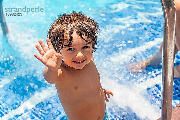 Zweijähriger Junge genießt den Sommer in einem Schwimmbad  lächelt im Urlaub vom Wasser