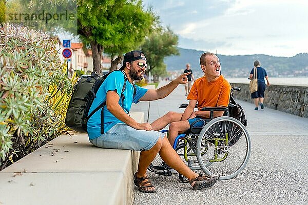 Behinderte Person im Rollstuhl mit Freunden im Sommerurlaub  die Spaß haben