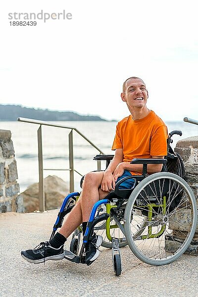 Porträt von ziemlich fröhlich behinderte Person im Rollstuhl am Strand im Sommerurlaub lächelnd