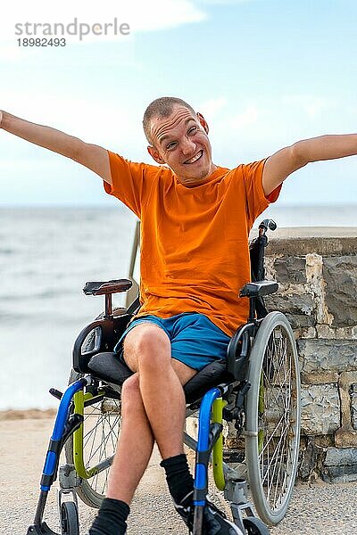 Porträt einer ziemlich fröhlichen behinderten Person im Rollstuhl am Strand in den Sommerferien