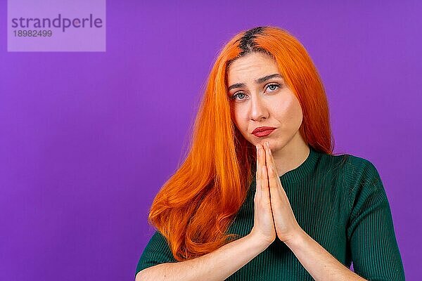 Rothaarige Frau im Studio Fotografie macht die Geste bitte auf einem lila Hintergrund