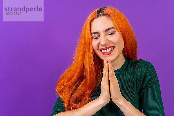 Rothaarige Frau im Studio Fotografie macht die Geste bitte auf einem lila Hintergrund