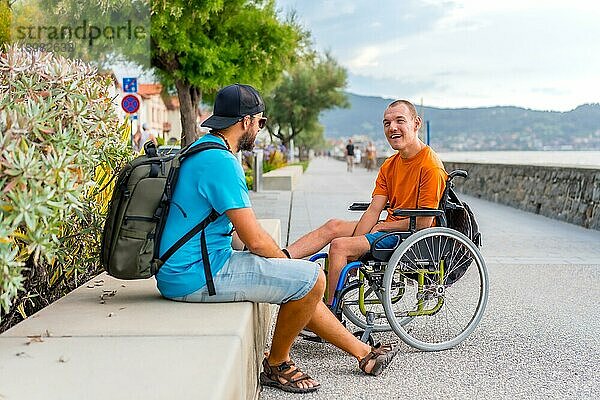 Eine behinderte Person im Rollstuhl mit einem Freund im Sommerurlaub