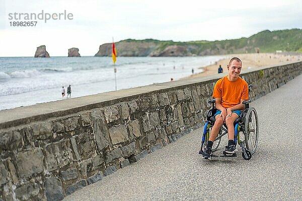 Eine behinderte Person im Rollstuhl am Strand  die im Sommer Spaß hat