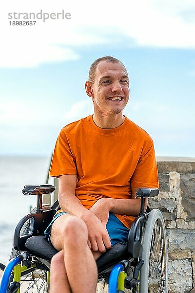 Porträt von ziemlich fröhlich behinderte Person im Rollstuhl am Strand im Sommerurlaub lächelnd