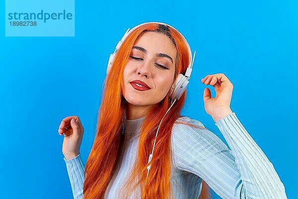 Rothaarige Frau im Studio Fotografie lächelnd tanzen auf einem blauen Hintergrund