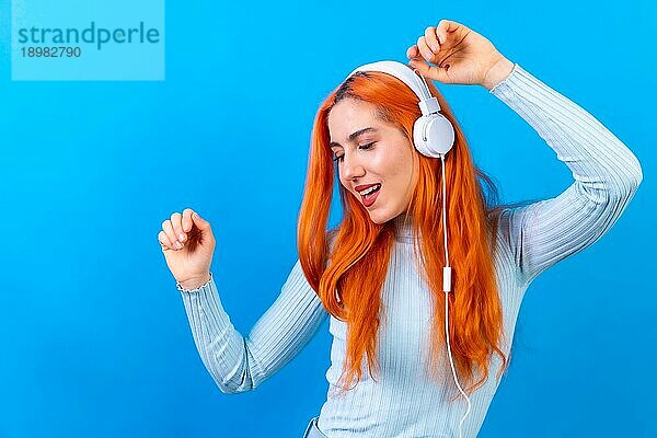 Rothaarige Frau im Studio Fotografie lächelnd tanzen auf einem blauen Hintergrund