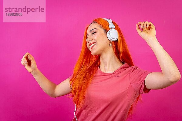 Rothaarige Frau im Studio Fotografie tanzen lächelnd auf einem rosa Hintergrund