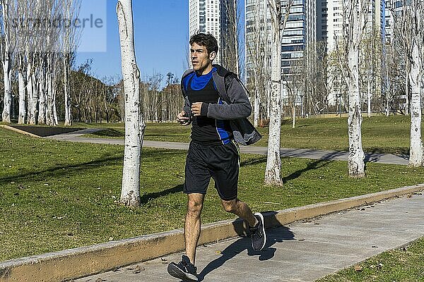 Junger attraktiver Athlet Sportler Läufer joggt am Morgen im öffentlichen Park