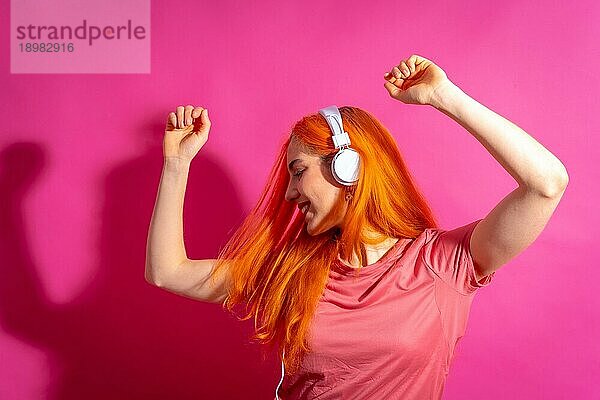 Rothaarige Frau im Studio Fotografie tanzen auf einem rosa Hintergrund  in harten Licht