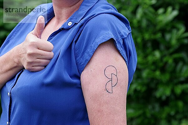 Tätowierung  Oberarm  Frau  Organspende  Tattoo  Haut  Eine Frau zeigt das tätowierte Symbol für Organspende auf ihrem Oberarm