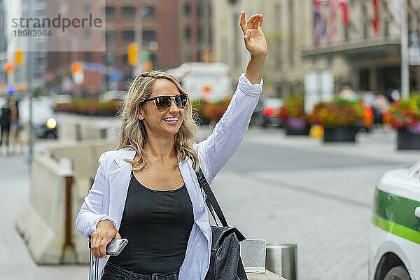 Ein schönes blondes Model genießt einen Tag auf Reisen und wartet auf ein Taxi