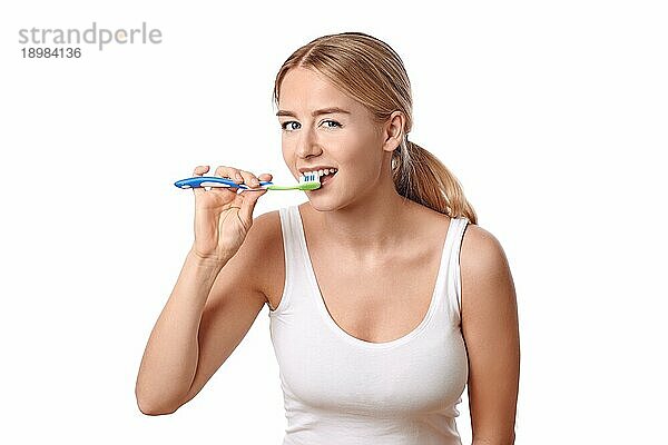 Attraktive Frau  die ihre Zähne mit einer Zahnbürste und Zahnpasta putzt  um Karies vorzubeugen  vor weißem Hintergrund