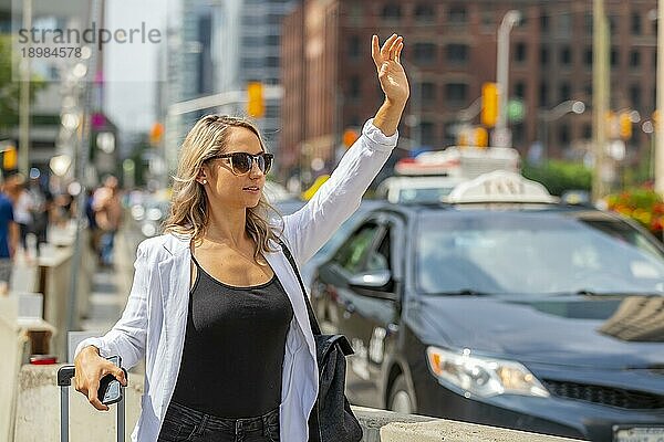 Ein schönes blondes Model genießt einen Tag auf Reisen und wartet auf ein Taxi