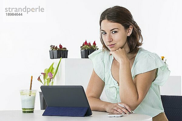 Eine Frau sitzt an einem Tisch und arbeitet mit ihren elektronischen Geräten