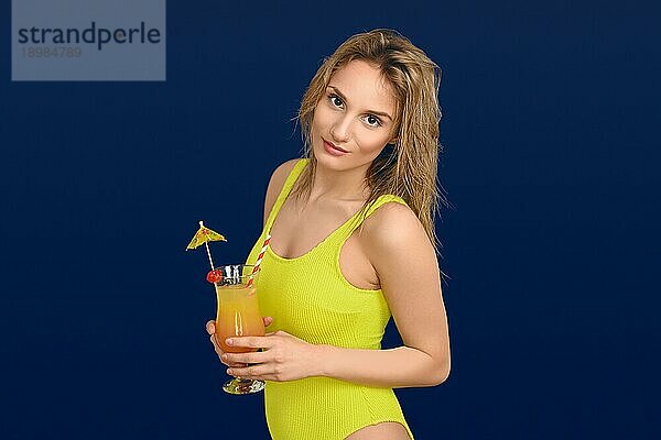 Attraktive trendige blonde Frau mit exotischen tropischen Cocktail in einem Glas  wie sie lächelt in die Kamera Konzept der Sommerurlaub