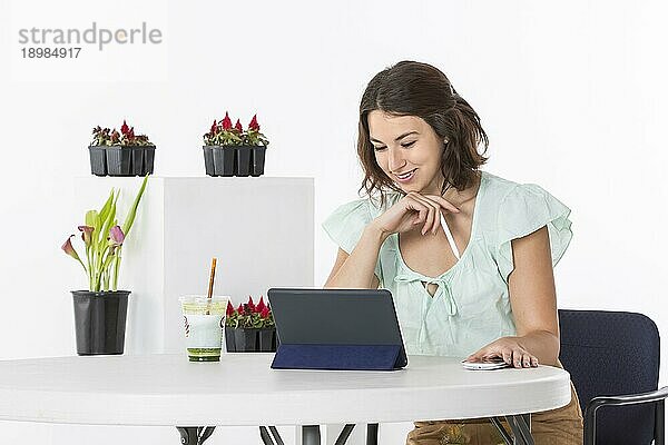 Eine Frau sitzt an einem Tisch und arbeitet mit ihren elektronischen Geräten