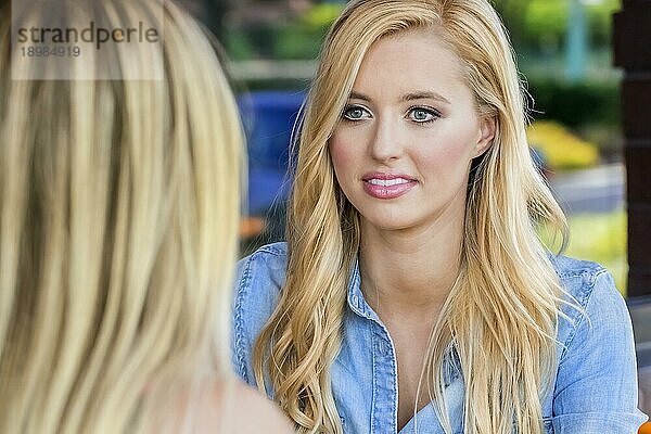 Ein blondes Modell  das in einem Café in einer städtischen Umgebung sitzt