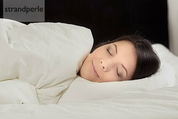 Attraktive junge Frau  die einen friedlichen Schlaf genießt und mit einem heiteren Ausdruck im Bett liegt und träumt