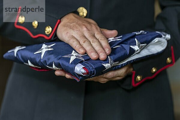 Eine weibliche Marinesoldatin in Militäruniform mit einer gefalteten amerikanischen Flagge