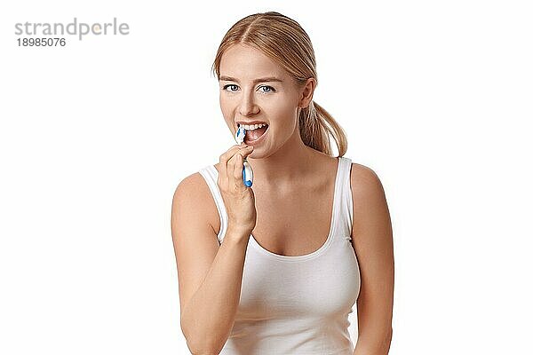 Attraktive Frau  die ihre Zähne mit einer Zahnbürste und Zahnpasta putzt  um Karies vorzubeugen  vor weißem Hintergrund