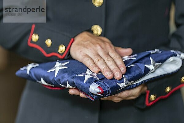 Eine weibliche Marinesoldatin in Militäruniform mit einer gefalteten amerikanischen Flagge