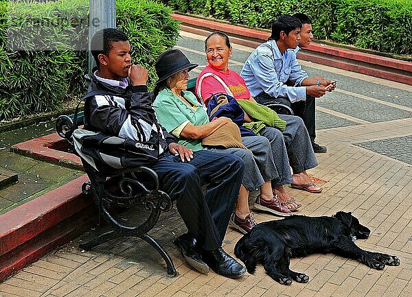 Republik Kolumbien  Colombia  Stadt Popayan  Departamento Cauca  Strassenszene in der Altstadt  Personen sitzen auf einer Bamk und Hund liegt davor  Kolumbien  Südamerika