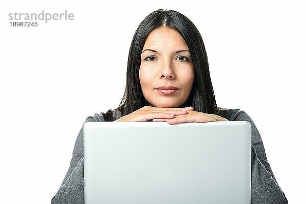 Glückliche junge Frau mit langen Haaren  die mit ihrem Laptop beschäftigt ist und in die Kamera schaut  vor weißem Hintergrund