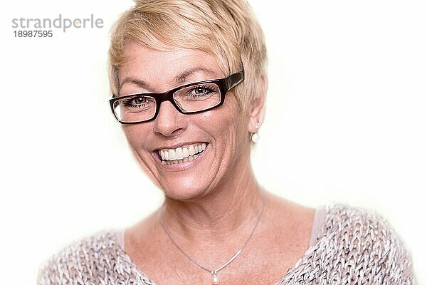 Kopf Schulter Porträt einer glücklichen  attraktiven blonden Frau mittleren Alters  die eine Brille trägt und mit einem schönen  lebhaften Lächeln in die Kamera schaut