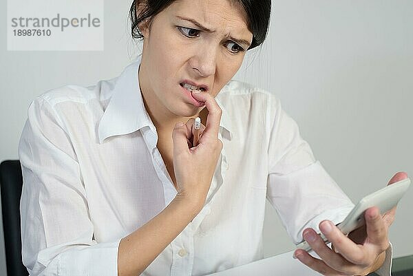 Verwirrte Frau denkt angestrengt nach und zieht eine Grimasse  während sie mit einem Taschenrechner in der Hand versucht  eine Antwort auf ein Problem zu finden