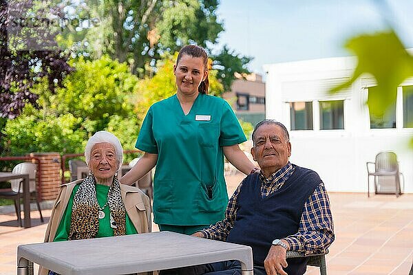 Porträt von zwei älteren Menschen mit der Krankenschwester im Garten eines Pflegeheims oder Seniorenheims  alter Mann und alte Frau