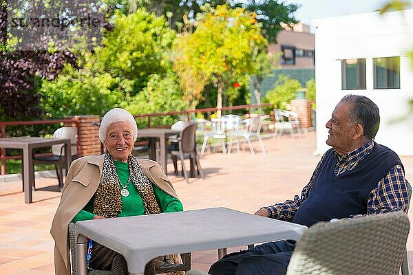 Zwei sehr fröhliche ältere Menschen im Garten eines Pflegeheims  die sich an einem sonnigen Sommertag ausruhen
