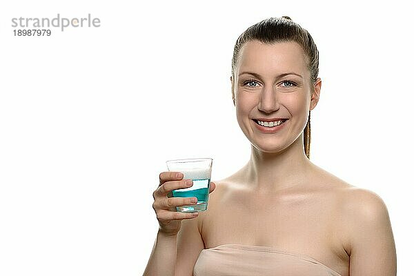 Close up Lächelnde junge Frau hält ein Glas Mundwasser in eine Kappe  während sie in die Kamera schaut  vor weißem Hintergrund
