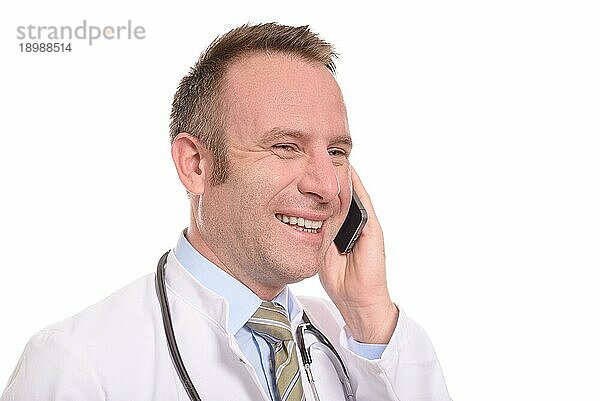 Männlicher Arzt mittleren Alters in Laborkittel und Stethoskop  der mit einem zufriedenen Lächeln einen Anruf auf seinem Mobiltelefon entgegennimmt  während er dem Gespräch zuhört  vor weißem Hintergrund