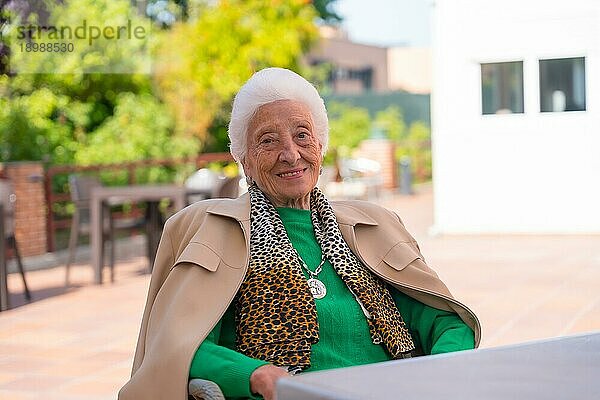 Porträt einer älteren Frau im Garten eines Pflegeheims an einem sonnigen Sommertag