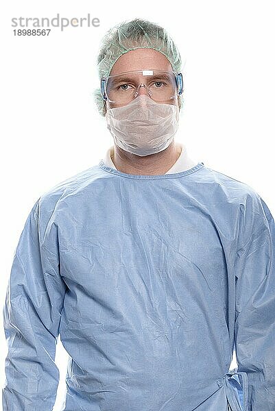 Krankenpfleger oder Arzt mittleren Alters in OP Kleidung mit OP Kittel  Maske  Schutzbrille und Kappe  der direkt in die Kamera schaut  Kopf und Schultern vor weißem Hintergrund