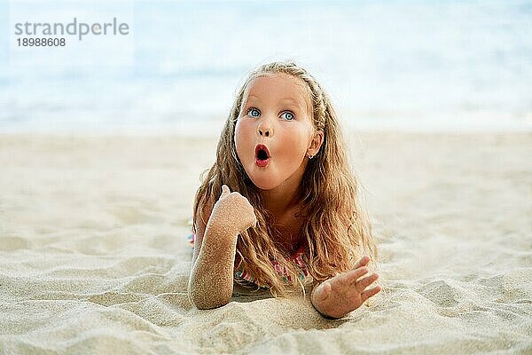 Überrascht niedlichen kleinen blonden Mädchen entspannen am Strand im Sommerurlaub. Lustige Kinder  wow Emotionen Konzept