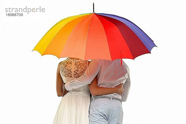 Dreiviertel Rückansicht eines romantischen Paares unter einem bunten Regenschirm  vor weißem Hintergrund