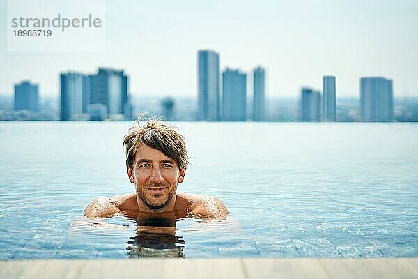 Hübscher Mann entspannt sich im Schwimmbad. Sommerurlaub Konzept