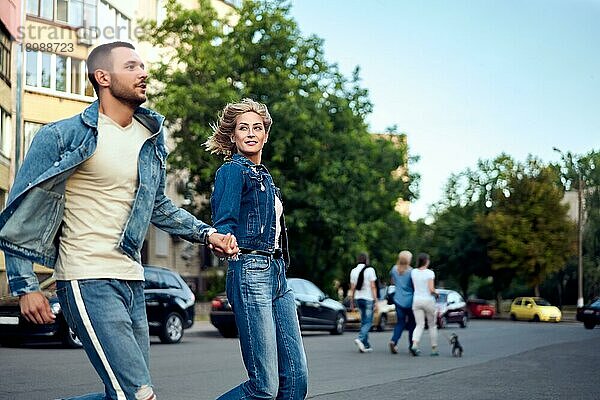 Junges glückliches Paar läuft über den Zebrastreifen auf der Straße Spaß  Wandern  Dating Konzept