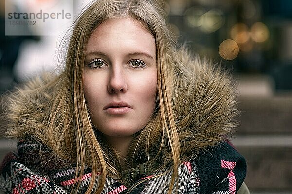 Attraktive ernste junge blonde Frau in einer warmen pelzigen Winterjacke  die direkt in die Kamera blickt  Nahaufnahme Kopf und Schultern