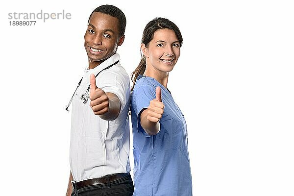 Enthusiastisches erfolgreiches multiethnisches medizinisches Team mit einem lächelnden afrikanischen Arzt und seiner hübschen Krankenschwester oder Assistentin  die mit einem glücklichen Lächeln die Daumen nach oben strecken  vor weißem Hintergrund