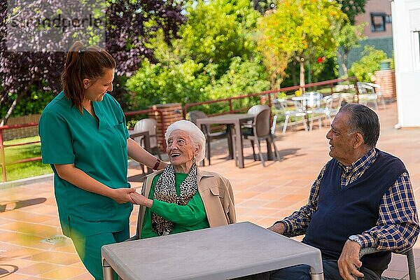 Zwei ältere Menschen mit der Krankenschwester im Garten eines Pflegeheims oder Seniorenheims  alter Mann und alte Frau