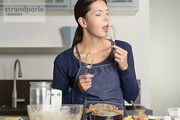 Close up Pretty Woman Backen in der Küche  Verkostung von Lebensmitteln auf Handmixer  während der Blick in die Kamera